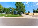 View of the home's garage and spacious driveway with a modern wooden fence for added privacy at 5601 E Colorado Ave, Denver, CO 80224