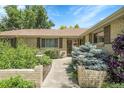 Charming home entrance with brick accents, lush landscaping, and decorative outdoor lighting at 1091 E Pinewood Ave, Centennial, CO 80121