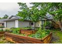Landscaped front yard featuring raised garden beds and mature trees, creating a serene and inviting curb appeal at 182 Lois Cir, Louisville, CO 80027