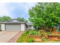 Landscaped front yard featuring garden beds and mature trees, creating a serene and inviting curb appeal at 182 Lois Cir, Louisville, CO 80027