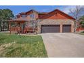 Charming two-story home featuring a stone facade, attached garage, covered porch, and well-maintained lawn at 7965 Lakeshore Dr, Parker, CO 80134
