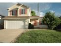 Inviting home with an attached garage, manicured lawn, and bright red door at 22030 Hill Gail Way, Parker, CO 80138