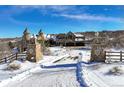 Stone pillars mark the entrance to a castle-style home in a winter setting at 3120 Bears Den Dr, Sedalia, CO 80135