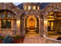 Stunning castle-style home entrance with arched wooden door, stone accents, and manicured landscaping at 3120 Bears Den Dr, Sedalia, CO 80135