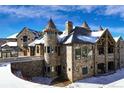 Stone castle-style home with snow covered landscaping and multiple towers at 3120 Bears Den Dr, Sedalia, CO 80135