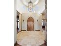 Impressive foyer with a grand arched wooden door, travertine flooring, and elegant chandelier at 3120 Bears Den Dr, Sedalia, CO 80135