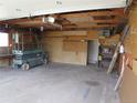 An empty garage features a lift, open ceiling, shelving, heater, and plenty of storage space at 5660 Olive St, Commerce City, CO 80022