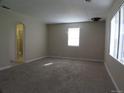 Spacious living room with neutral-colored walls, new carpet, and a doorway to the bathroom at 5660 Olive St, Commerce City, CO 80022