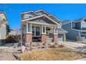 Charming two-story home featuring a covered porch with brick accents and a well-maintained front lawn at 11712 Lewiston St, Commerce City, CO 80022