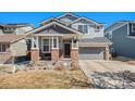 Charming two-story home featuring a covered porch with brick accents and a well-maintained front lawn at 11712 Lewiston St, Commerce City, CO 80022
