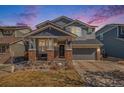 Charming two-story home featuring a covered porch with brick accents and a well-maintained front lawn at 11712 Lewiston St, Commerce City, CO 80022