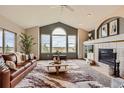 Bright living room with vaulted ceilings, large windows showcasing the view, and a cozy fireplace at 3487 Willownook Ranch Trl, Elizabeth, CO 80107