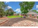A spacious backyard featuring mature trees, a landscaped garden, and a brick patio at 3 Glenview Dr, Littleton, CO 80123