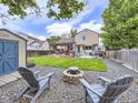 Spacious backyard featuring a stone firepit, Adirondack chairs, deck with a pergola, and a lush grassy area at 11395 E 116Th Dr, Commerce City, CO 80640