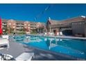 Community pool area with lounge chairs, tables, and a clear blue swimming pool on a sunny day at 2896 W Riverwalk Cir # 204, Littleton, CO 80123