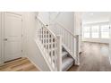 Staircase featuring carpeted steps, white banister, and neutral decor with view to beautiful wood floors beyond at 1889 Water Birch Way, Castle Rock, CO 80108