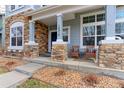 Inviting front porch with stone pillars, wicker furniture, and attractive landscaping at 14214 Lakeview Ln, Broomfield, CO 80023