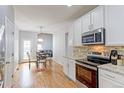 Open kitchen with stainless appliances, granite counters, and hardwood floors opens to dining and living areas at 14214 Lakeview Ln, Broomfield, CO 80023