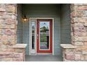 Inviting front entry featuring a red door flanked by stone columns and a charming exterior light fixture at 18601 E Water Dr # A, Aurora, CO 80013