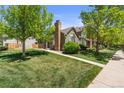 Exterior view of home featuring a lush green lawn and mature trees at 9636 W Chatfield Ave # C, Littleton, CO 80128
