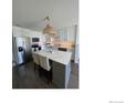 Modern kitchen with a spacious island, stylish lighting, stainless steel appliances, and a bright backsplash at 9637 E 56Th Pl, Denver, CO 80238