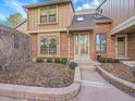 Attractive townhome displaying a brick front, trimmed bushes, and a cozy entryway with glass-paneled door at 8166 E Phillips Ave, Centennial, CO 80112