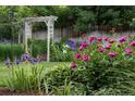 Lush backyard featuring vibrant flower gardens, a wooden fence, and an attractive pergola, perfect for outdoor enjoyment at 7189 S Kline St, Littleton, CO 80127
