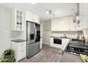 Bright kitchen featuring white cabinets, stainless steel appliances, and herringbone floors at 6314 Brooks Dr, Arvada, CO 80004
