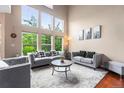 Bright living room with soaring windows, hardwood floors, and stylish gray sofas at 3000 E 112Th Ave # 86, Northglenn, CO 80233