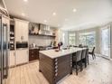 Modern kitchen with stainless steel appliances, large island with seating, and bright lighting at 7053 S Shawnee St, Aurora, CO 80016