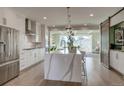 Modern white kitchen with a central waterfall island, stainless steel appliances, and an open living area at 5880 Beeler Ct, Denver, CO 80238