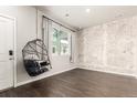 Stylish living room features dark wood floors, a painted brick accent wall, and an eye-catching hanging chair at 1353 Reynolds St # 16B, Fort Lupton, CO 80621