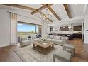 Bright living room with beamed ceilings, seamless indoor/outdoor flow, and views into the modern kitchen at 27381 E Lakeview Dr, Aurora, CO 80016