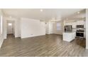 Open-concept living area featuring hardwood floors, white walls, and stainless steel appliances at 816 Leeward St, Lochbuie, CO 80603