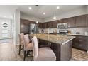 Bright kitchen features stainless steel appliances, a kitchen island with barstool seating, and dark wood cabinets at 10062 Southlawn Cir, Commerce City, CO 80022
