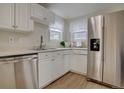 Bright kitchen boasts stainless steel appliances, white cabinets, and durable wood-look flooring at 1275 S Wolff St, Denver, CO 80219