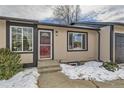 Front entrance of a ranch home with a red door and snow on the ground at 6196 W 66Th Ave, Arvada, CO 80003