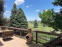 Relaxing back deck featuring a cozy lounge chair, fire pit, and scenic views of the lush golf course and distant horizon at 12000 Pine Top St, Parker, CO 80138