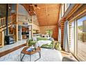 Open-concept living space with a log-beamed ceiling, gas fireplace, and natural light at 9868 Overlook Rd, Sedalia, CO 80135