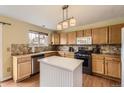 Functional kitchen featuring wooden cabinets, stone backsplash, stainless appliances, and a practical kitchen island at 20910 Omaha Ave, Parker, CO 80138
