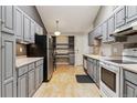 Well-lit kitchen with gray cabinets, updated appliances, and a dining nook, creating a functional space at 12062 E Maple Ave, Aurora, CO 80012