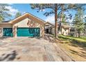 Beautiful home featuring a green garage door, stone driveway, and mature trees at 1653 Gore Dr, Larkspur, CO 80118
