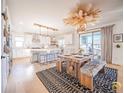 Open concept kitchen with an island, breakfast bar, stainless appliances, modern lighting, and a rustic dining table at 3439 W 154Th Ave, Broomfield, CO 80023