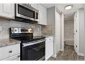 Modern kitchen featuring stainless steel appliances and white cabinetry with a glimpse into the bathroom at 3100 S Federal Blvd # 331, Denver, CO 80236
