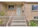 A close-up of a brick home's front entrance steps and pink railing, showcasing a secure door at 2710 Zenobia St, Denver, CO 80212