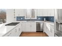 Modern kitchen with stainless steel appliances, white cabinetry, quartz countertops and a blue backsplash at 11989 E Lake Cir, Greenwood Village, CO 80111