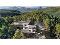 Beautiful exterior view of modern mountain home surrounded by lush evergreen trees with stunning mountain backdrop at 13415 S Resort Dr, Conifer, CO 80433