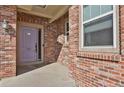 Close up of a brick home's entryway with a lavender door, side window, and classic outdoor lighting at 247 N Coolidge Way, Aurora, CO 80018