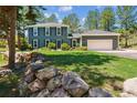 Charming two-story home with manicured lawn, rock features, and lush trees at 7701 Rollins Dr, Larkspur, CO 80118