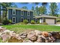 Charming two-story home with manicured lawn, rock features, and lush trees at 7701 Rollins Dr, Larkspur, CO 80118